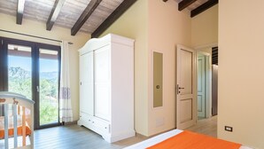 A bedroom with a bed, a wardrobe, a door leading to another room, and a view through a glass door. - Apartment Casa Sole with Mountain View, Wi-Fi, Garden & Terrace (Dorgali)