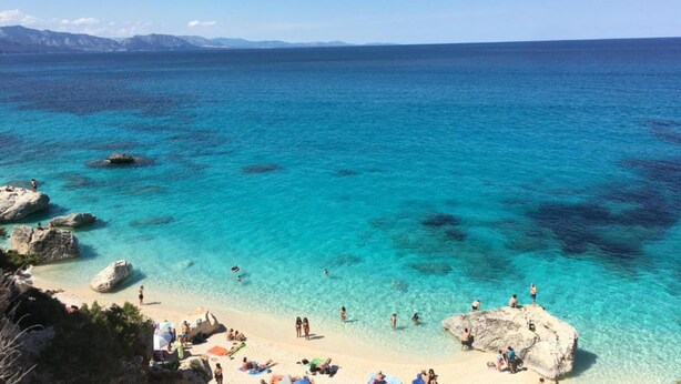 A beach with clear turquoise water, rocky formations, and people sunbathing. - Apartment Casa Sole with Mountain View, Wi-Fi, Garden & Terrace (Dorgali)