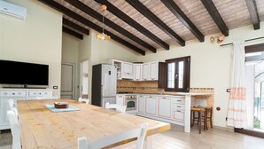 A kitchen with a wooden table, white cabinets, and a built-in oven. - Apartment Casa Sole with Mountain View, Wi-Fi, Garden & Terrace (Dorgali)