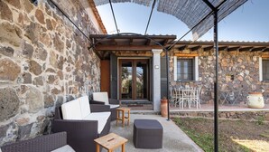 A stone exterior with a covered patio, wicker furniture, and a stone wall. - Apartment Casa Sole with Mountain View, Wi-Fi, Garden & Terrace (Dorgali)