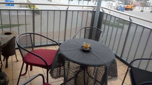 Un balcón con mesa y sillas, con vistas a un puerto deportivo con barcos y edificios.