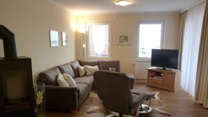 Una sala de estar con sofá, sillón, televisor y chimenea.