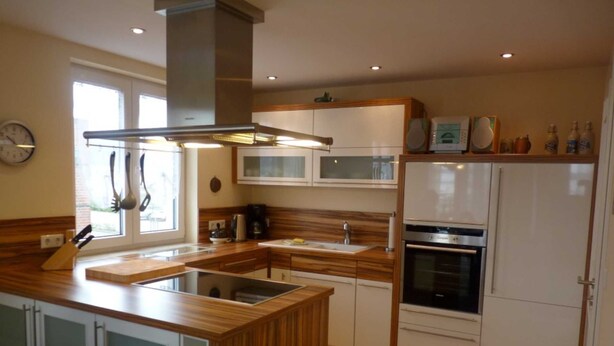 Una cocina moderna con una isla central, electrodomésticos integrados y un ventanal que proporciona luz natural.
