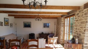 Un salon chaleureux avec une table à manger en bois, des chaises, un canapé, une cheminée et des murs en pierre.