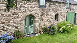 Un bâtiment en pierre avec une porte verte, une petite fenêtre et une autre porte verte sur le côté.