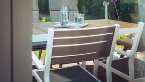 Un espace extérieur aménagé pour prendre les repas, avec une table, des chaises et un parasol.