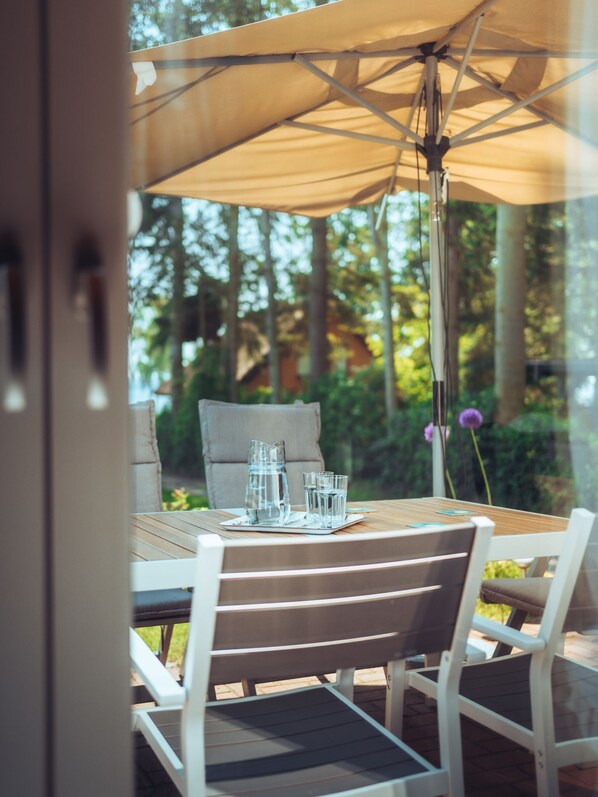 Un espace extérieur aménagé pour prendre les repas, avec une table, des chaises et un parasol.