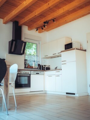 Une cuisine moderne avec des armoires blanches, une cuisinière noire et un plafond en bois.