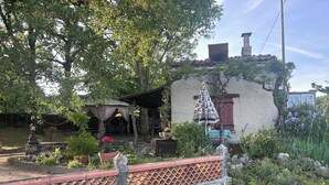 Een rustiek huis met een stenen muur, een tuin met plantenpotten en een pergola.
