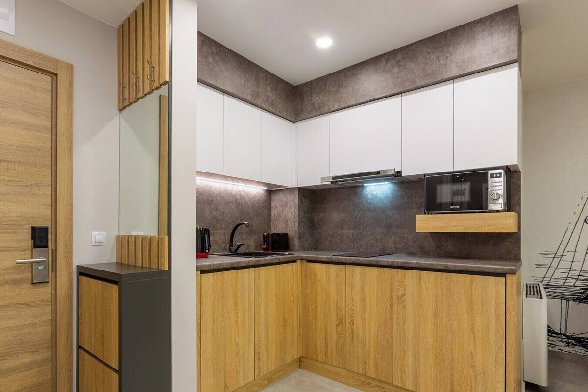A modern kitchen with wooden cabinets, a built-in microwave, and a stainless steel sink.