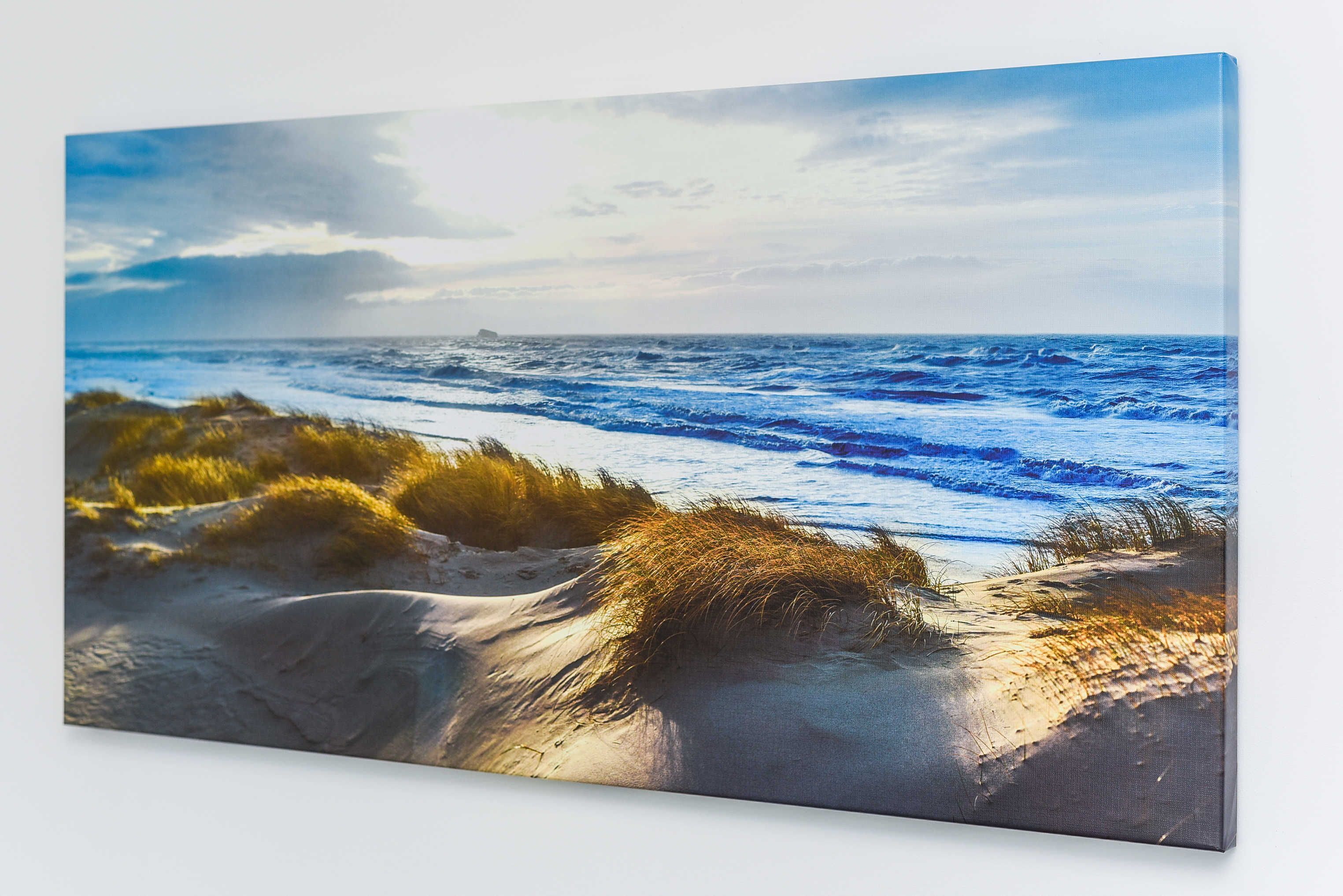 A beach scene with sand dunes and the ocean.