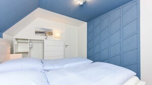 Una camera da letto con un letto, una cassettiera, uno specchio e una parete con motivo geometrico.