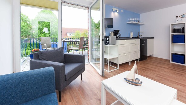 Un appartamento moderno con balcone, angolo cottura e zona pranzo.