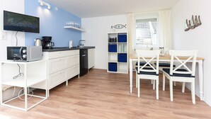 Una cucina compatta con TV, macchina del caffè e zona pranzo con sedie e tavolo.