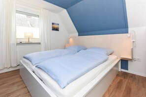 Quarto com cama, janela com cortinas, luminária na parede e radiador.
