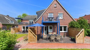 Una casa in mattoni con un patio, mobili da esterno e un ombrello blu.