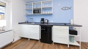 Una cucina moderna con mobili bianchi, una lavastoviglie nera, un forno a microonde e una macchina da caffè.