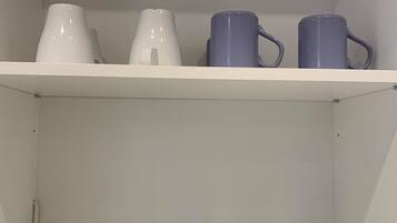 Una estantería con tazas blancas y azules y varios frascos de vidrio transparentes.