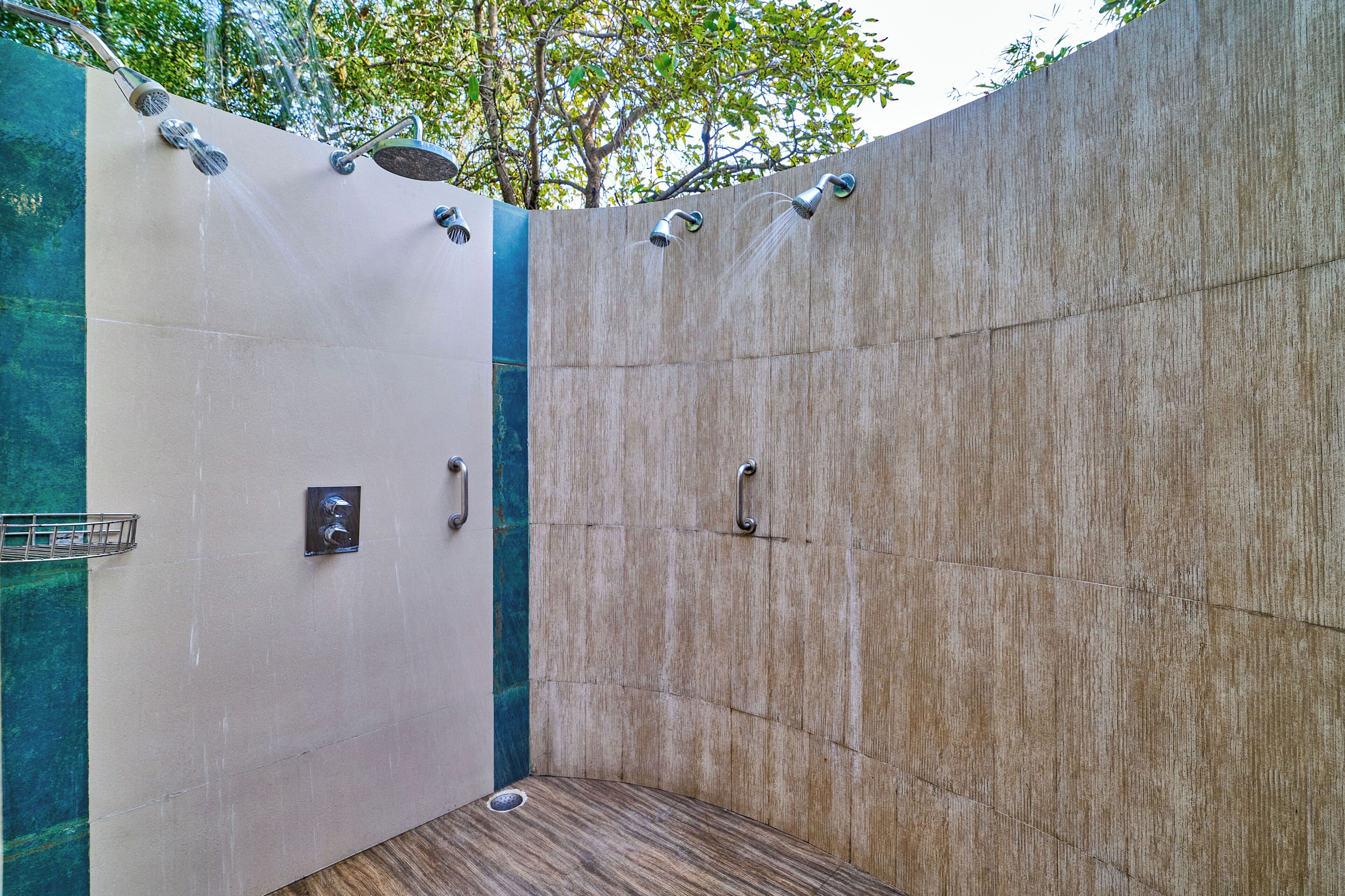 A shower area with multiple heads, a handrail, and a drain.