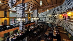 A restaurant with high wooden ceilings, stone walls, and multiple dining areas with tables and chairs.