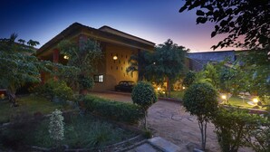 A hotel with a well-maintained garden, a paved driveway, and a car parked in front.