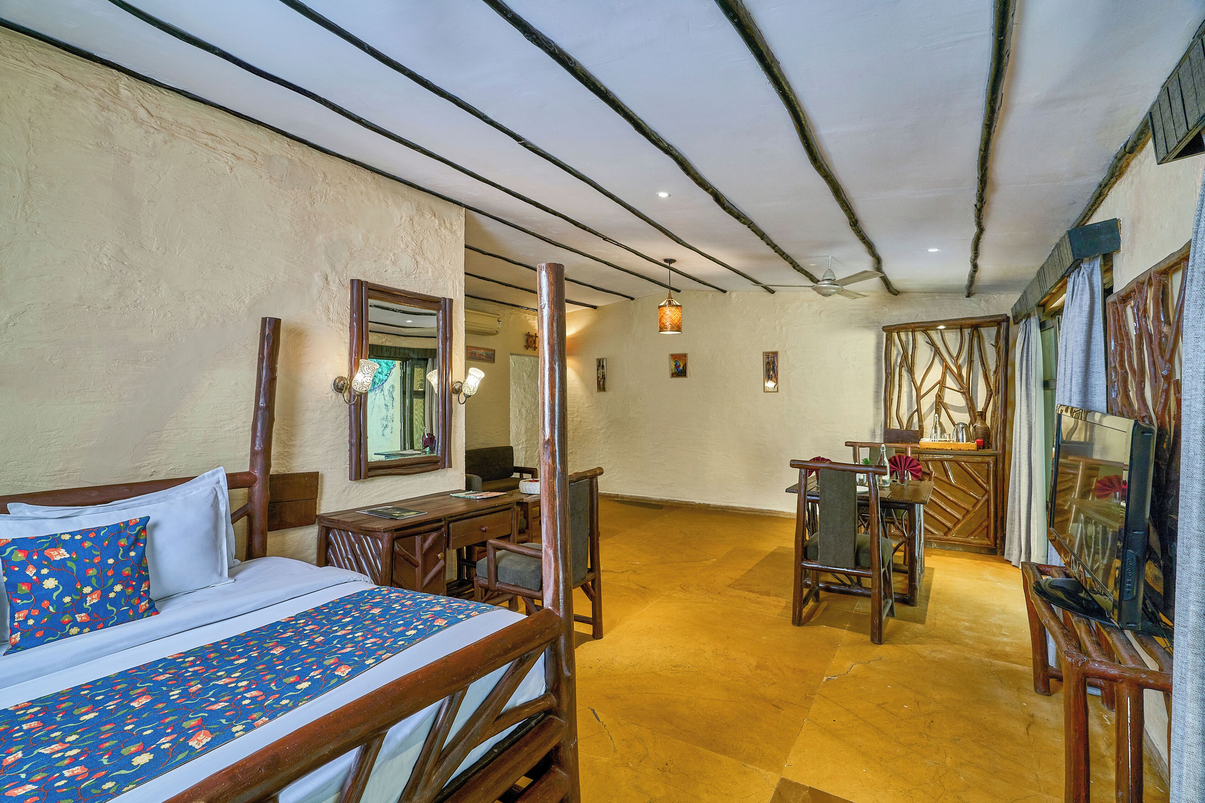 A hotel room with a bed, desk, chair, television, and a dining area.