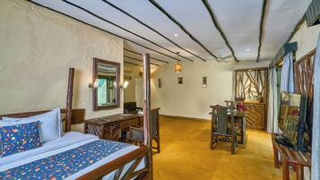A hotel room with a bed, desk, chair, television, and a dining area.