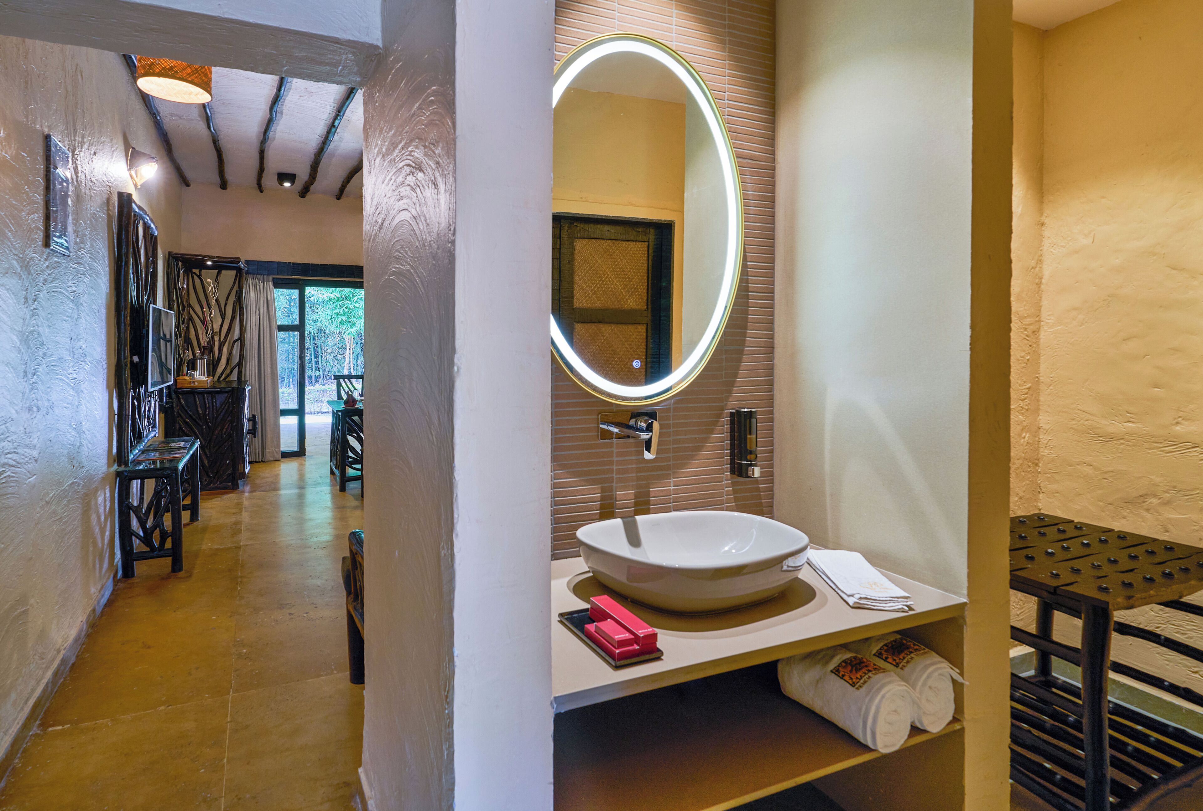 Une salle de bain avec un grand miroir ovale, un lavabo blanc et un porte-serviettes.