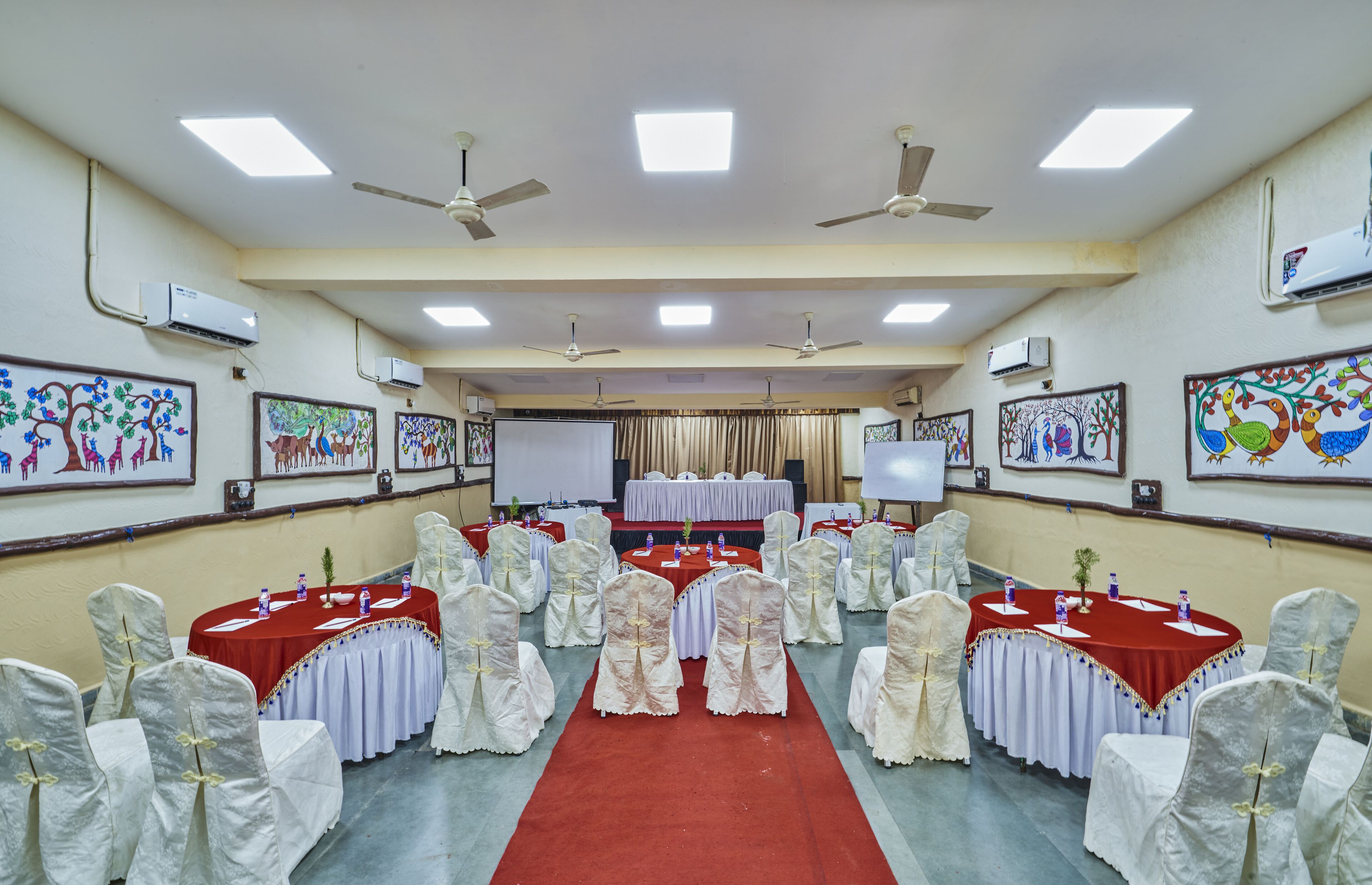 A conference room with round tables, white chairs, and red carpets.
