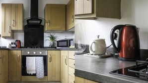 A kitchen with wooden cabinets, a black range hood, a microwave, a kettle, and a stove. - The cottage is a short walk to the Station, with trains to Liverpool / chester,  (Wirral, Merseyside)