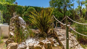 A rocky garden with a central plant, surrounded by various trees and a rope barrier. - Casa el Altico, Lujosa Casa Rural con Unas Vistas Increíbles en Plena Naturaleza (Cehegín)