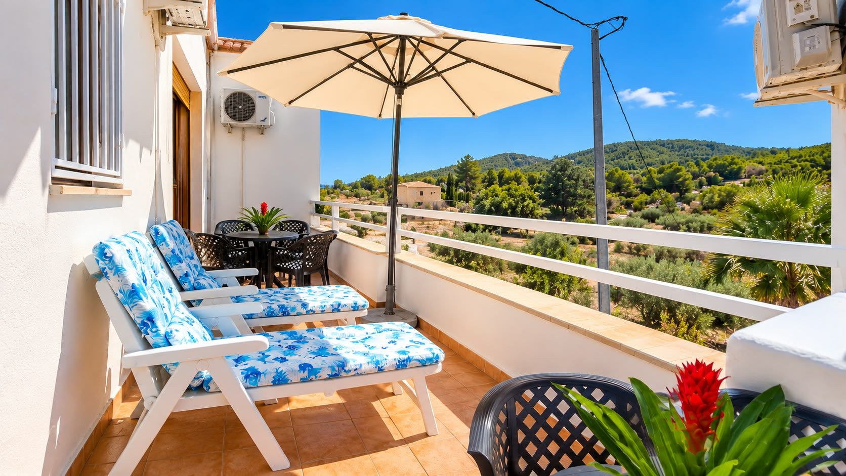 Un balcon avec deux fauteuils, une table et un parasol.