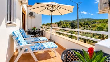 Un balcon avec deux fauteuils, une table et un parasol.