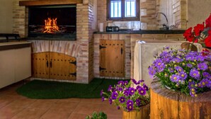 A kitchen with a stone fireplace, wooden cabinets, and a window. - Casa el Altico, Lujosa Casa Rural con Unas Vistas Increíbles en Plena Naturaleza (Cehegín)