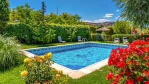 A rectangular swimming pool surrounded by lush greenery, with a clear blue sky above. - Casa el Altico, Lujosa Casa Rural con Unas Vistas Increíbles en Plena Naturaleza (Cehegín)