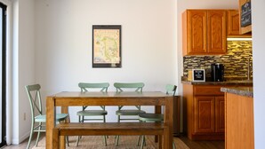 A dining area with a wooden table and chairs, a rug, and a map on the wall.
