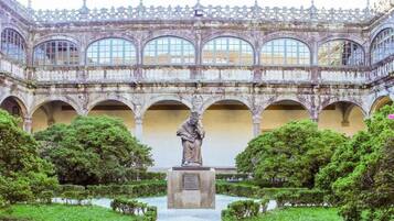 Un patio con una estatua, arcos y una fuente.