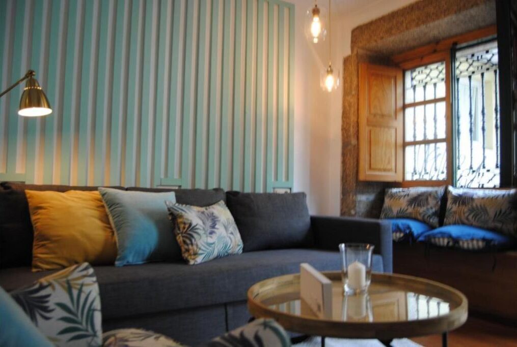 A cozy living room with a grey sofa, patterned cushions, and a round coffee table with a glass top.