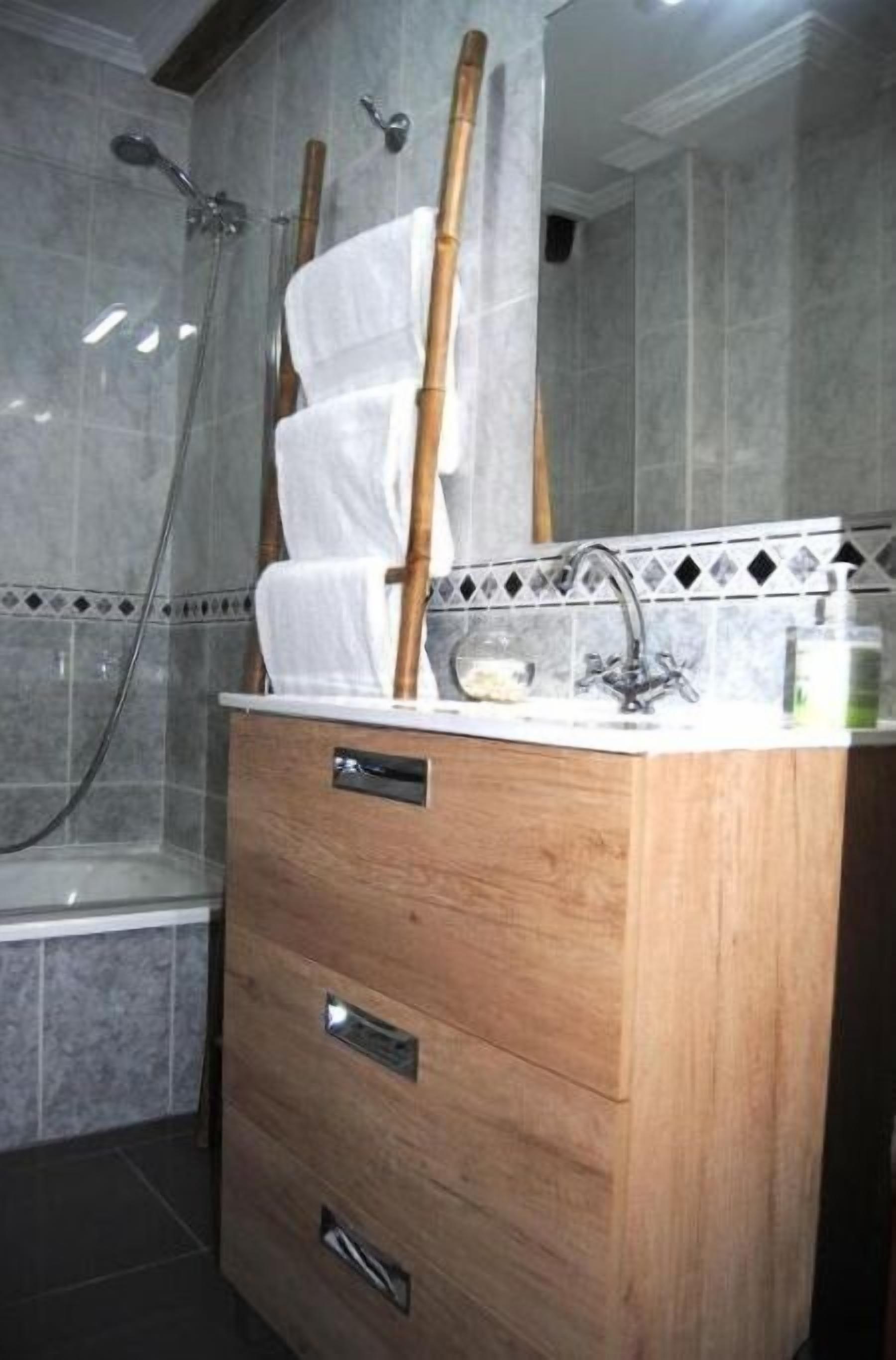 Un baño con tocador de madera, ducha y salpicadero de azulejos.