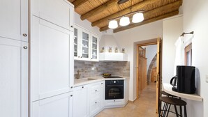 A kitchen with white cabinets, a black oven, and a wooden ceiling.