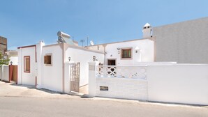 A white building with a gated entrance, a satellite dish, and a small tower-like structure on the roof.