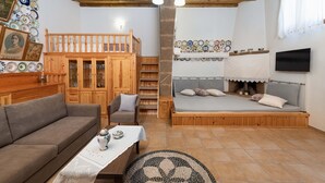 A cozy room with a sofa, a wooden bed, a dining table, and a staircase leading to a loft.