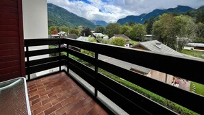 A balcony with a view of a mountainous landscape and houses.