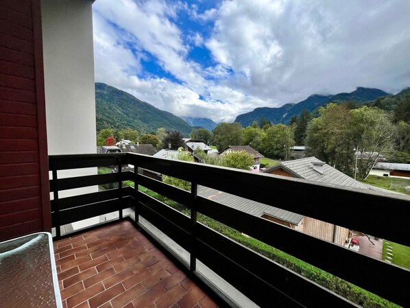 A balcony with a view of a mountainous landscape and houses.
