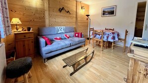 A cozy room with a wooden wall, a sofa, a small table, a lamp, and a picture on the wall.