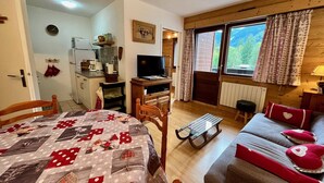 A cozy room with a bed, a sofa, a TV, and a dining area.