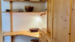 A wooden kitchen with a countertop, a stool, and a cabinet.