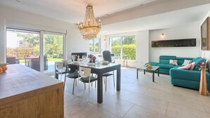 Ein geräumiger Wohnbereich mit Esstisch, Stühlen, einer Couch und einer Kandelaber.