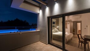 Ein modernes Hotelzimmer mit Balkon, einem Bett, einem Schreibtisch und einer Kristallleuchter.
