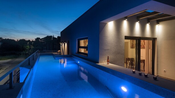 Ein modernes Haus mit Swimmingpool, hellem Innenraum und Blick auf die umliegende Landschaft.